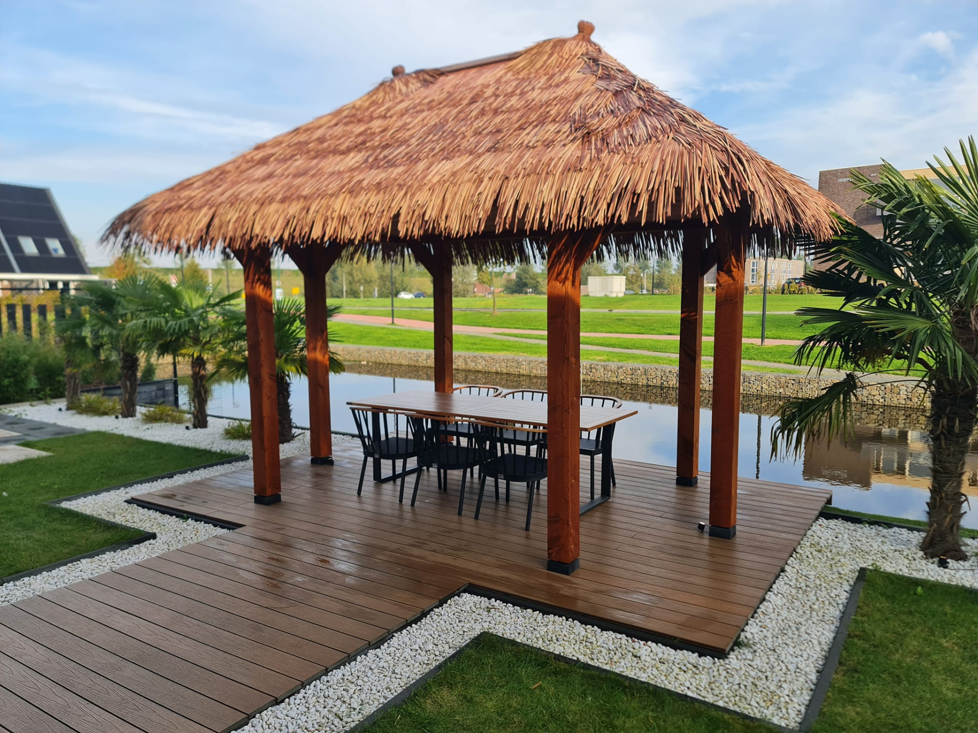 Houten palapa met rieten dak en dinertafel in een door Heja Hoveniers aangelegde tuin